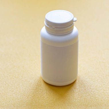 Tablet ilaç şişesi, sarı arka planda izole edilmiş bir fotoğraf. Model.