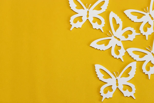 The concept of nature in spring. Minimal flatley composition, top view. White butterflies on a yellow background, a creative minimal concept, copy space.