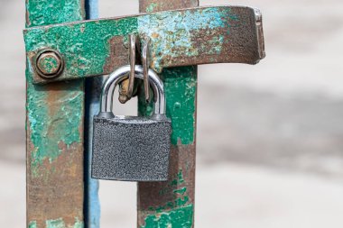 Kapalı ve kilitli kapı ızgarası gümüş asma kilitle. Menteşelerin üzerindeki metal bir kilit ızgaranın üzerinde asılı duruyor. Güvenlik kavramı veya yasağı, tasarımınız için kopyalama alanı