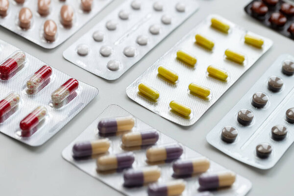 Vitamins and tablets in blister packs, close-up. Blurred background, place to insert text. Modern healthcare and pharmacy.