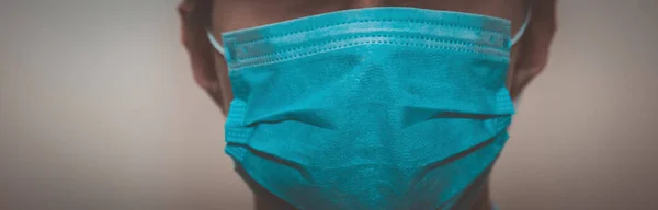 Young man in a medical mask smiles, portrait, close up, health care concept