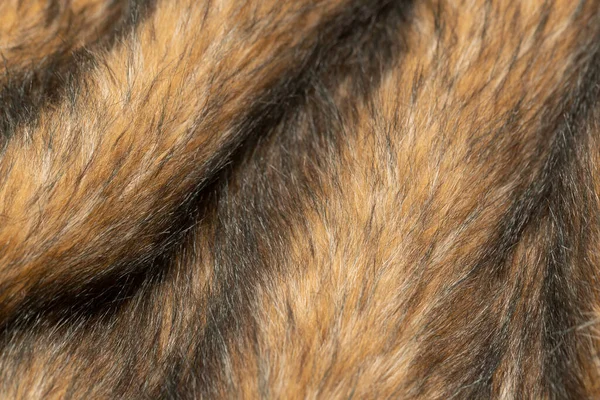 Close-up of a fluffy dark brown faux fur fabric with a background texture. Brown artificial fabric, can be used as a background. Fur for toys or clothing. Eco-friendly replacement of natural fur.