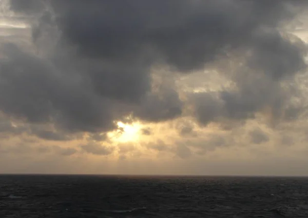 Evening landscape. Sea, sunset through the clouds and cloudy sky in the photo. Sea background.