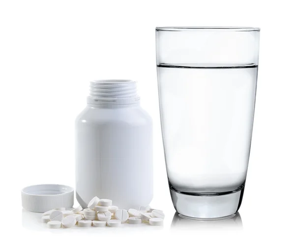 Pills spilling out of pill bottle and Glass of water — Stock Photo, Image