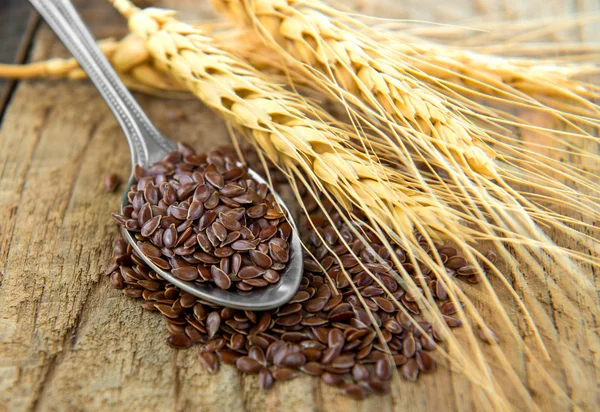 Flaxseeds i sked på trä bord — Stockfoto