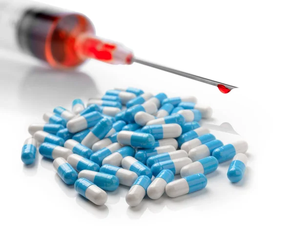 Capsules de pilules et seringue en plastique avec liquide rouge isolé sur w — Photo