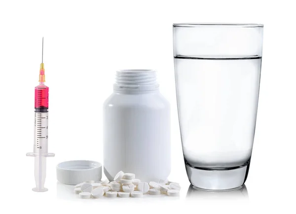 Prášky, linoucí se z pilulku láhev a sklenice vody — Stock fotografie