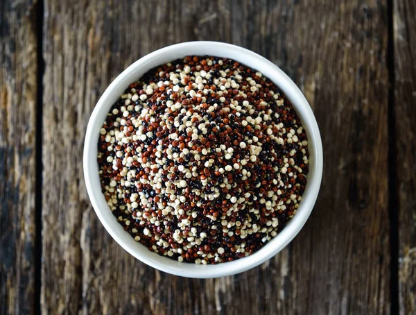 Quinoa seeds in bowl on wood — Stock Photo, Image