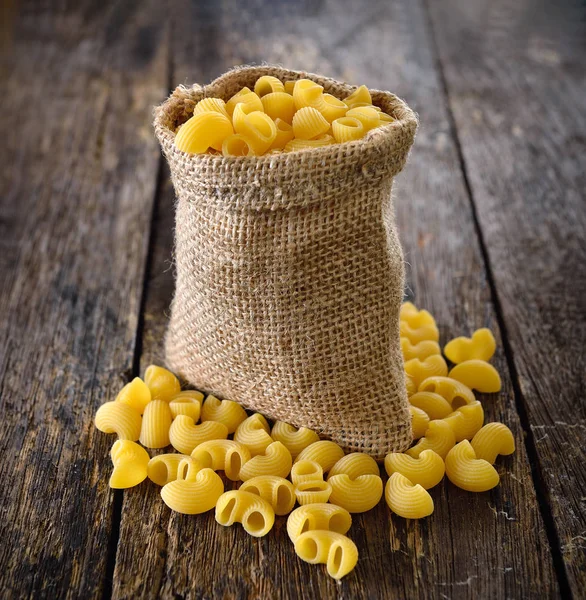 Macaroni In the sack on wood — Stock Photo, Image