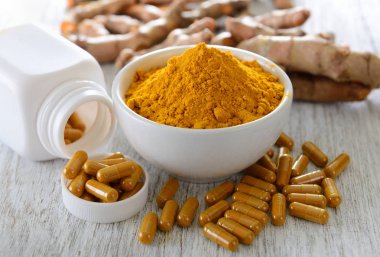 Tahta zemin üzerinde zerdeçal tozu ve zerdeçal kapsülleri