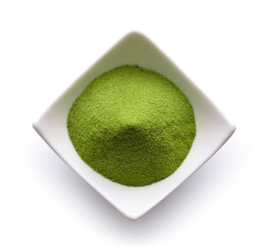 Beyaz arka planda bir kasede yeşil çay tozu