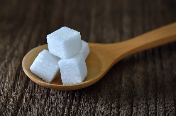 Sugar cubes in wood spoon on wood table — Stock Photo, Image