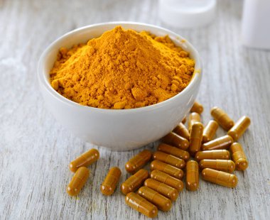 Tahta zemin üzerinde zerdeçal tozu ve zerdeçal kapsülleri