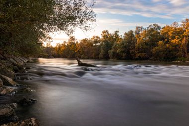 Günbatımında ağaçlar ve nehirlerle sonbahar manzarası.
