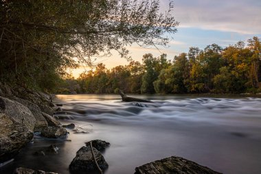 Günbatımında ağaçlar ve nehirlerle sonbahar manzarası.