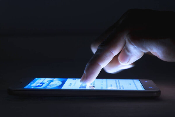 Closeup of a male hand using smartphone use social media at night at home for searching social networks
