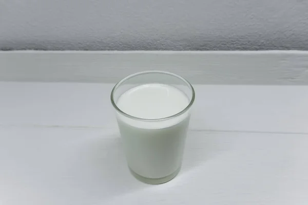 白い木製のテーブルの上に置かれた新鮮な牛乳のガラス飲む準備ができて — ストック写真