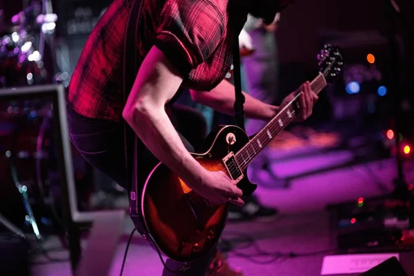 Η ροκ μπάντα παίζει στη σκηνή. Κιθαρίστας, μπασίστας και ντραμς. Ο κιθαρίστας παίζει. — Φωτογραφία Αρχείου