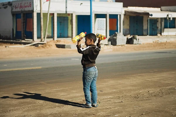 Aguejgal, Marocco - 17 gennaio 2020: Ragazzo che vende petrolio per strada nel piccolo villaggio . — Foto Stock