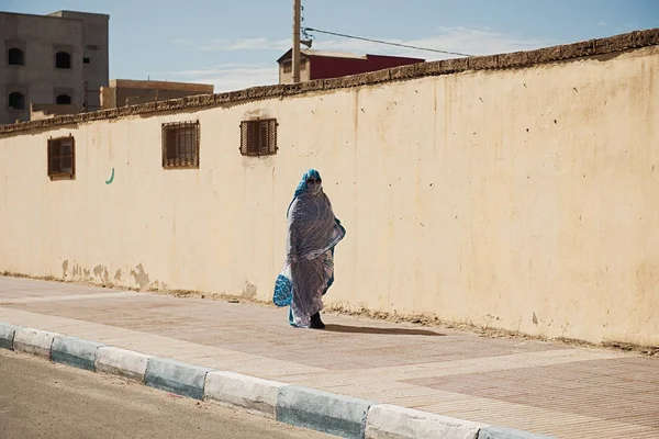 Women walking down the street, wearing beautiful blue and white Arab clothes. Buildings background. — 스톡 사진