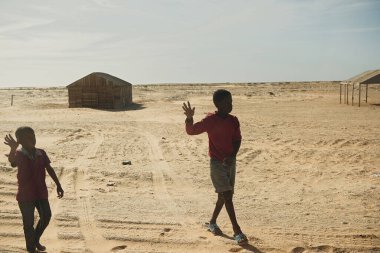 Nouadhibou, Moritanya, 18 Ocak 2020: Tanımlanamayan çocuklar yol kenarındaki köyde el sallıyorlar.