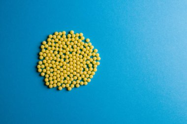 Mavi arka planda sarı haplar ve metin için fotokopi alanı. Alternatif homeopati ilacı, sağlık ve sağlık konsepti. Seçici odak