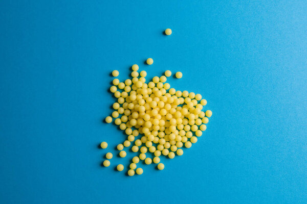 Желтые медицинские таблетки на синем фоне с пространством для копирования текста. Альтернативная гомеопатия медицина, здравоохранение и оздоровительный концепт. Селективный фокус
