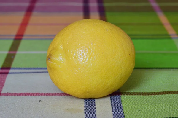 Fresh fruits: a single lemon on a colored tablecloth