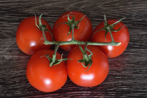 一束西红柿 枝条放在黑暗的切菜板上 — 图库照片