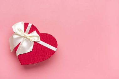 Kırmızı kalp şeklinde hediye kutusu, pembe arka planda kurdele kurdelesi, düz manzara Sevgililer günün kutlu olsun, doğum günün kutlu olsun, bayanların tatil kartı.