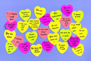 Mor renkli sevgililer günü arkaplanı için çeşitli yazıtlara sahip renkli kalp çıkartmalarının üst görünümü