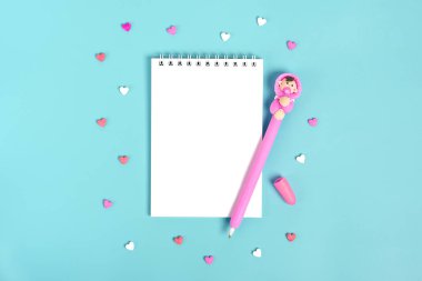 Düz yatıyordu, boş defter ve pembe kalemle bebek tasarımı ve dağınık kalpler mavi arka planda, Sevgililer Günü konsepti ve bebek duşu üstte..