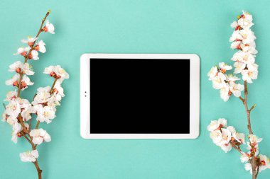 Çiçekli kayısı ağacı buketi, yeşil arka planda beyaz tablet. Mesaj için yer. Düz yatış Mock up.