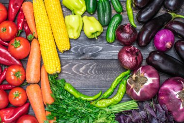 biber, domates, mısır, havuç, yeşil salata, kişniş, patlıcan, salatalık, fesleğen, dereotu, soğan gibi çeşitli taze meyve ve sebze çeşitleri sıralanmıştır. Sağlıklı gıda konsepti.