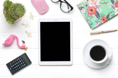Merkez ofis çalışma alanı. Tablet, hesap makinesi, not defteri, altın kalem ve ataç, gözlük, flamingo biblo, bir fincan kahve, sulu, beyaz ahşap zeminde bilgisayar faresi. Üst görünüm Düzleştir.