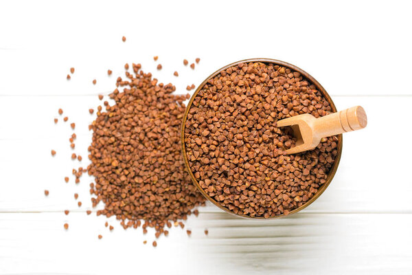 brown buckwheat grains in wooden bowl on isolated white background Healthy food, superfood concept