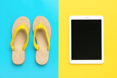 Yüzme aksesuarları - moda yaz terliği, mavi ekran siyah tablet, sarı arka planda düz konum Üst görünüm seyahat, tatil, çevrimiçi rezervasyon konsepti.