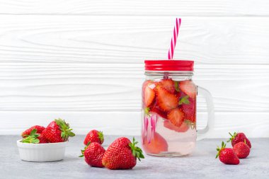 Çilekli su, kokteyl, limonata ya da çay. Beyaz ahşap zemin üzerinde çilek, limon ve nane yaprağı olan soğuk yaz içeceği. Düz yatıyordu.