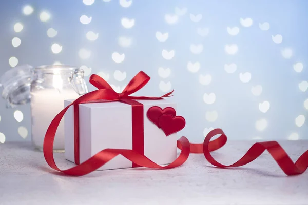 Белая подарочная коробка с сердцами, красной лентой и свечой — стоковое фото