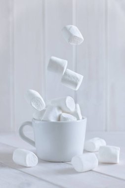 Marshmallow beyaz arkaplanda bardağa düşüyor