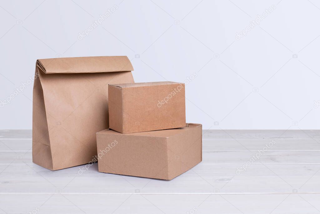 Cardboard boxes and paper bag isolated on white wooden background