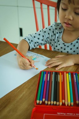 Çocuk beyaz kağıda aile resmini çiziyor..