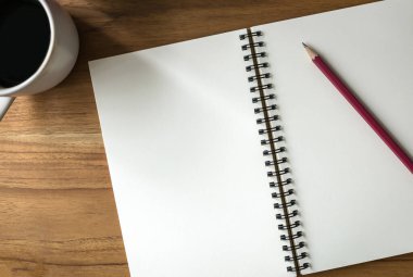 Spiral defter, kalem, kahve fincanı, ahşap masa, senin için boş alan.