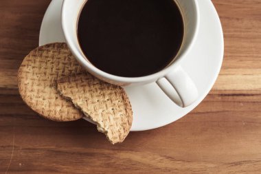 Tahta masada bisküvili bir fincan kahve.