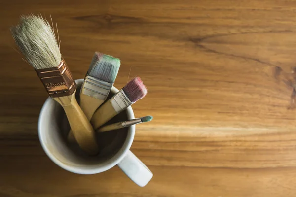 paint brushes in a coffee cup