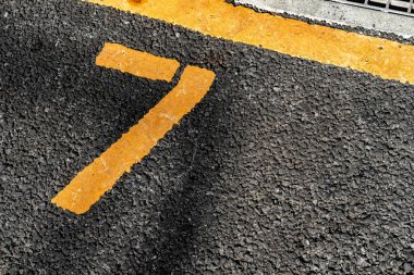 Asfalt otoparkı, sarı çizgili ve sarı numara 7, 7, 7..