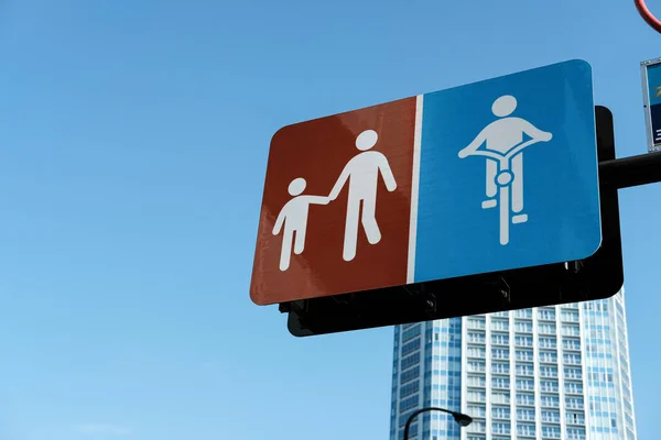 青い空を背景に子供の看板や自転車レーンの看板の手を歩く大人のシンボル — ストック写真