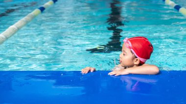 Yüzme havuzunda yüzme sınıfındaki mutlu çocuk..