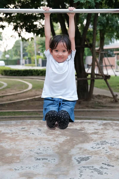 かわいいアジアの子供は 村の公園の遊び場でプルアップバーにぶら下がっています 子供のためのスポーツ屋外活動 — ストック写真