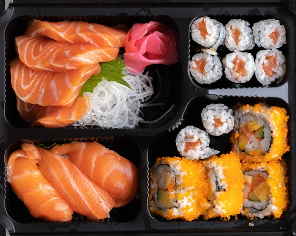 Bento box set of Sushi, Sashimi, California roll, Maki sushi roll. Japanese food made from Raw fish in A Single-portion takeout or take home meal.